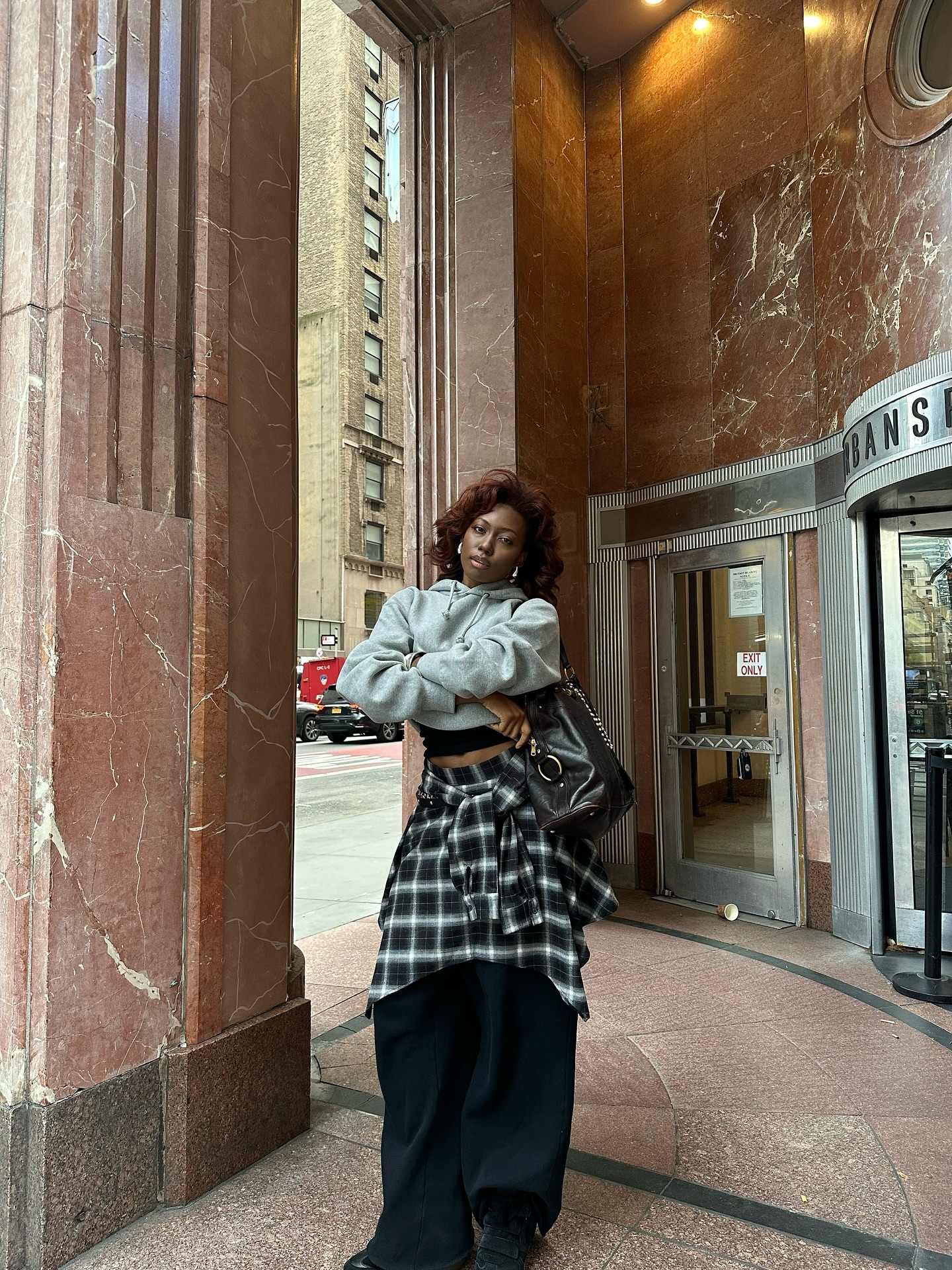 Influencer Chanel McKinsie wearing a plaid shirt over trousers with a grey hoodie.
