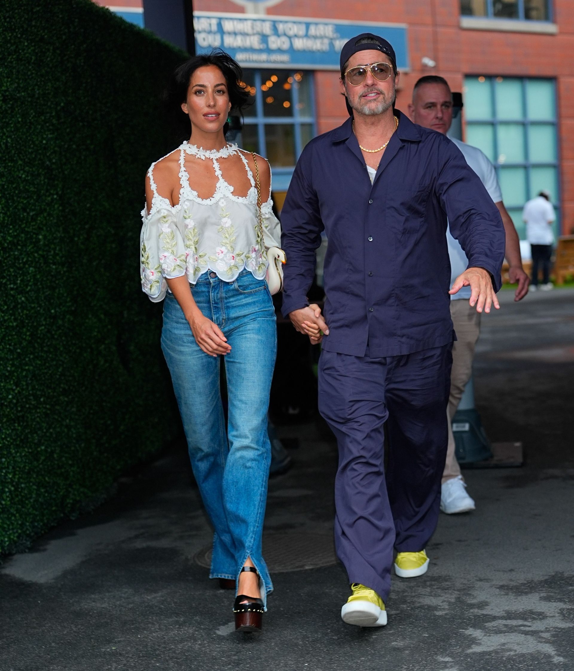 Ines de ramon wears a white top, split-hem jeans, wood heels and brad pitt wear sa blue jacket and pants with yellow sneakers.