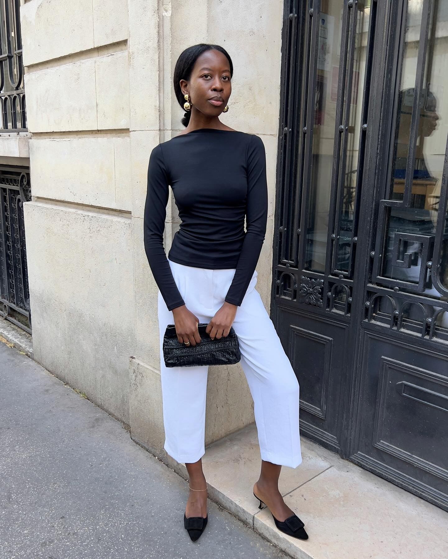 Woman in a black boat neck top and white pants
