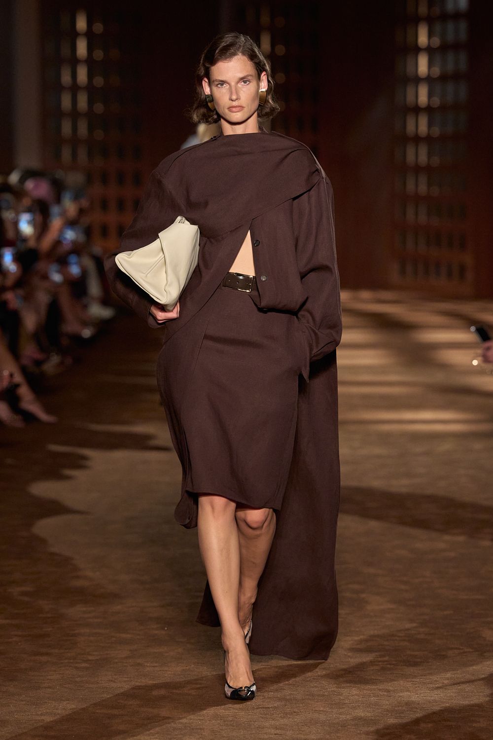 a woman carries a clutch bag at the ferragamo spring 2027 show.