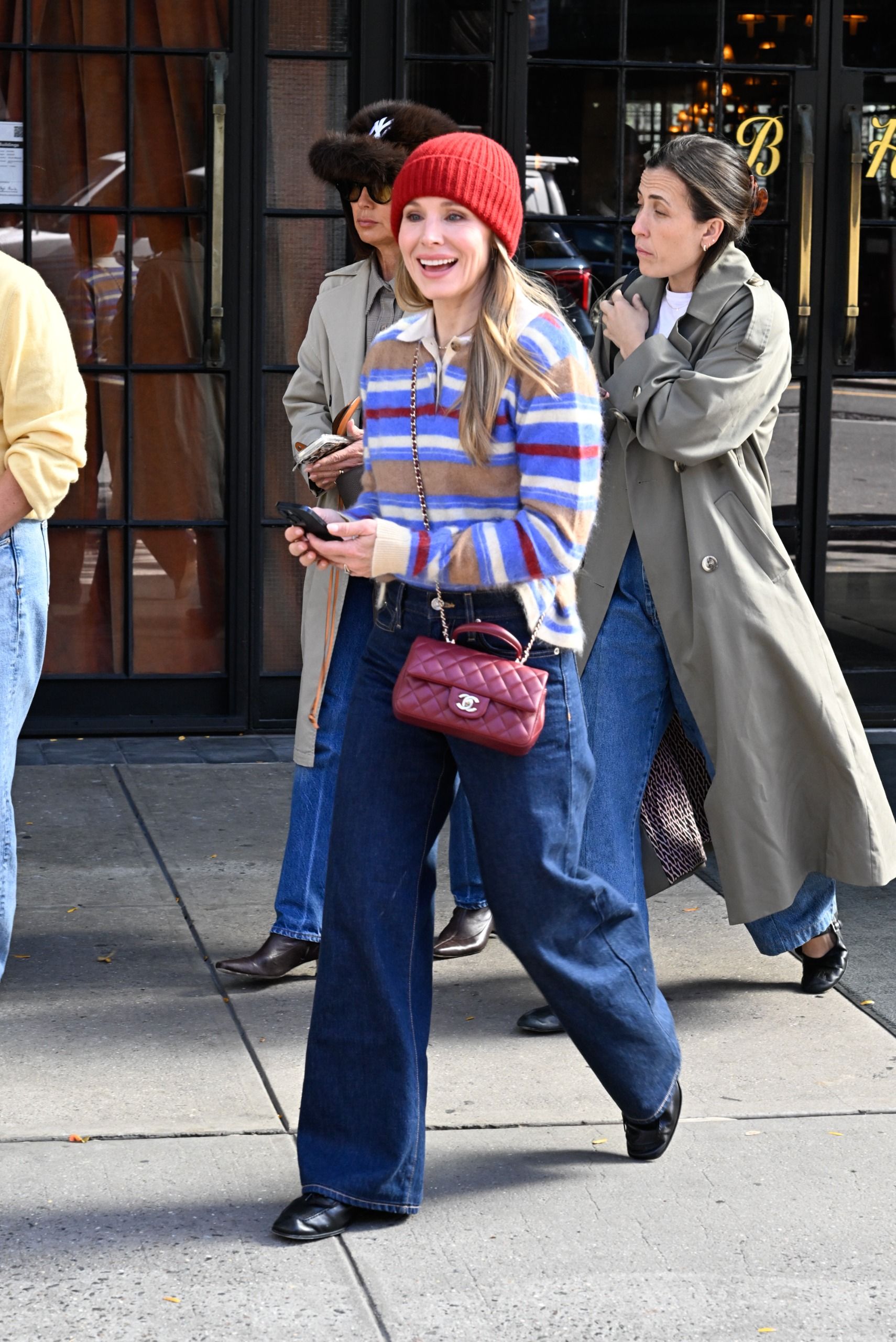 Kristen Bell walks outside wearing a striped polo jumper with indigo jeans, a burgundy Chanel bag and black slim-line leather trainers.