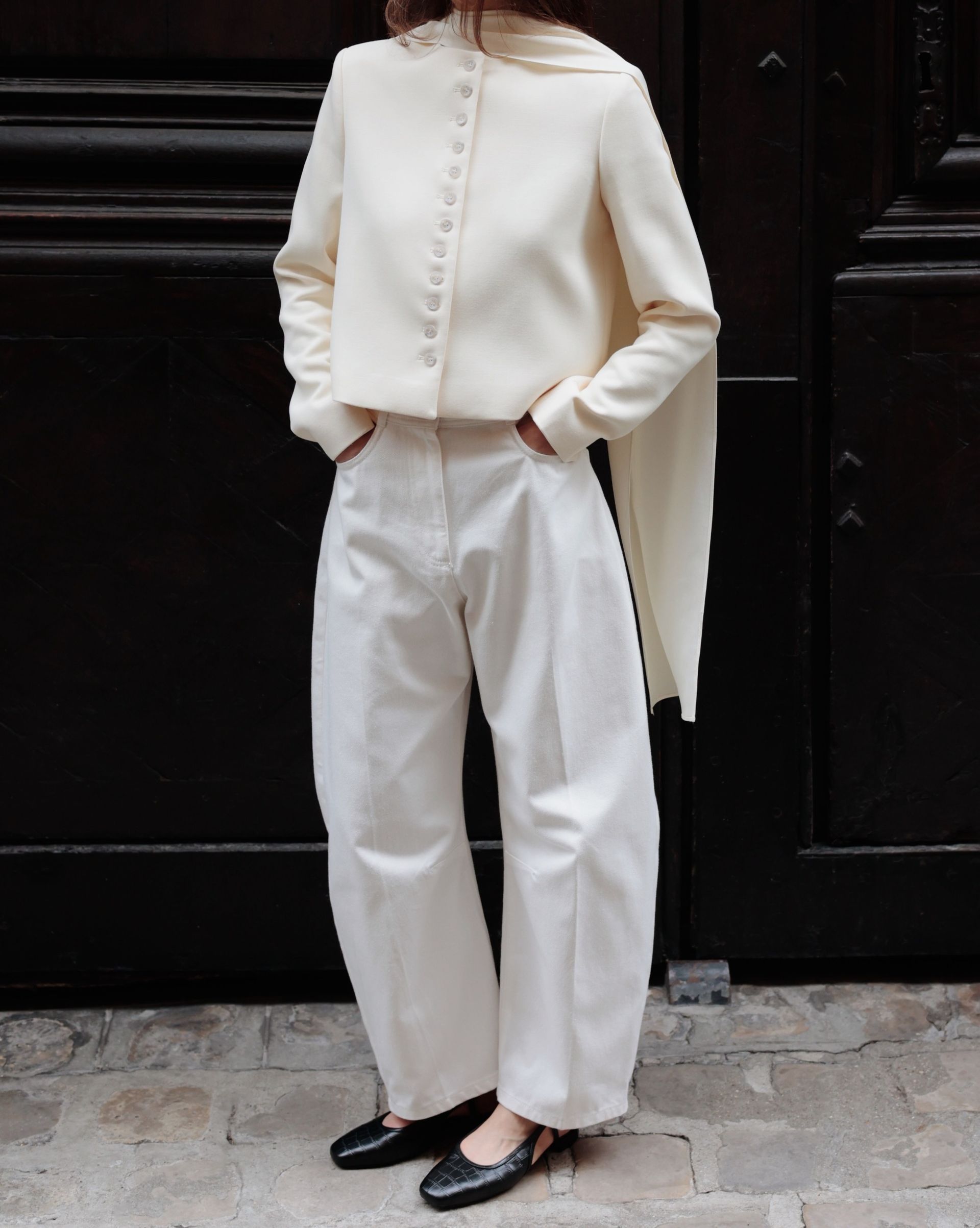 Woman wears cream jacket, cream trousers, black ballet flats