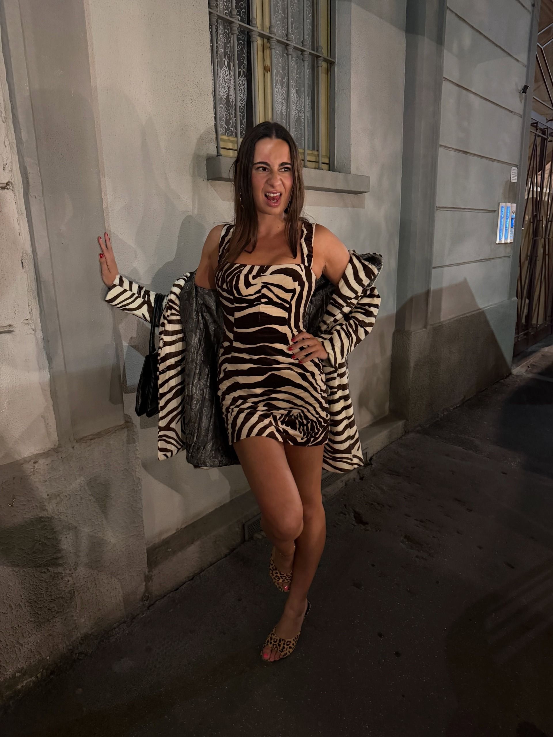 Woman wearing a zebra-print dress and matching coat.