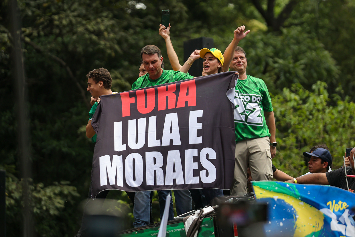 Flavio Bolsonaro holds a flag reading ''Fora Lula e Moraes'' (''Lula and Moraes Out'') during a campaign event in Sao Paulo, Brazil, October 18, 2026