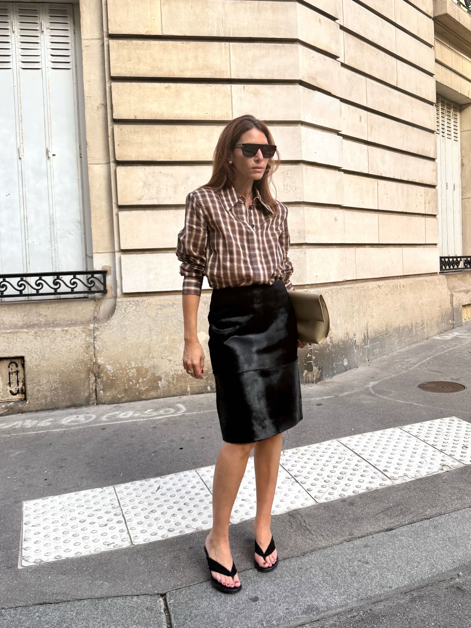 Woman in a plaid shirt and knee-length skirt.