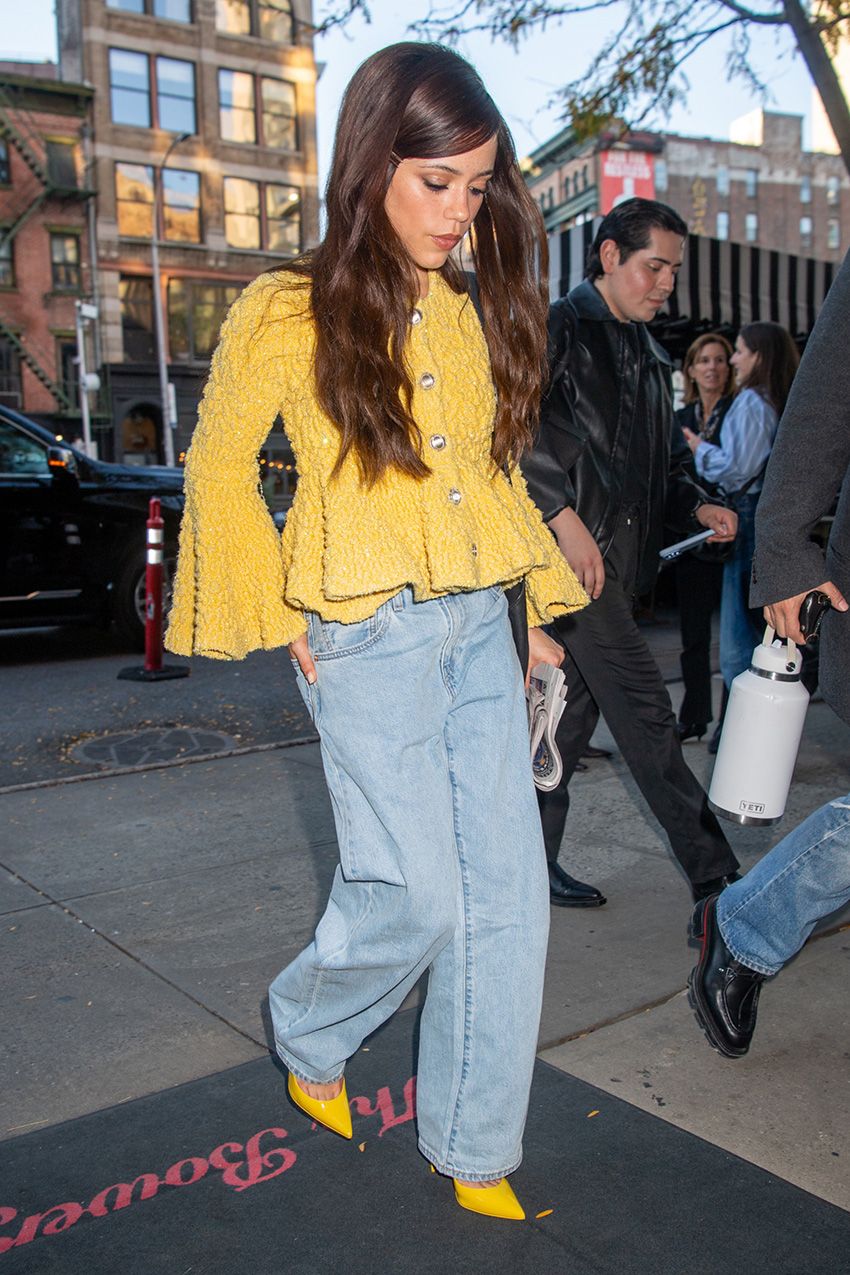 Jenna Ortega wearing jeans, a yellow sweater, and matching yellow pumps