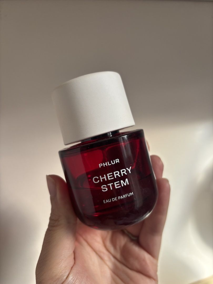 Mica Ricketts holding bottle of Phlur Cherry Stem