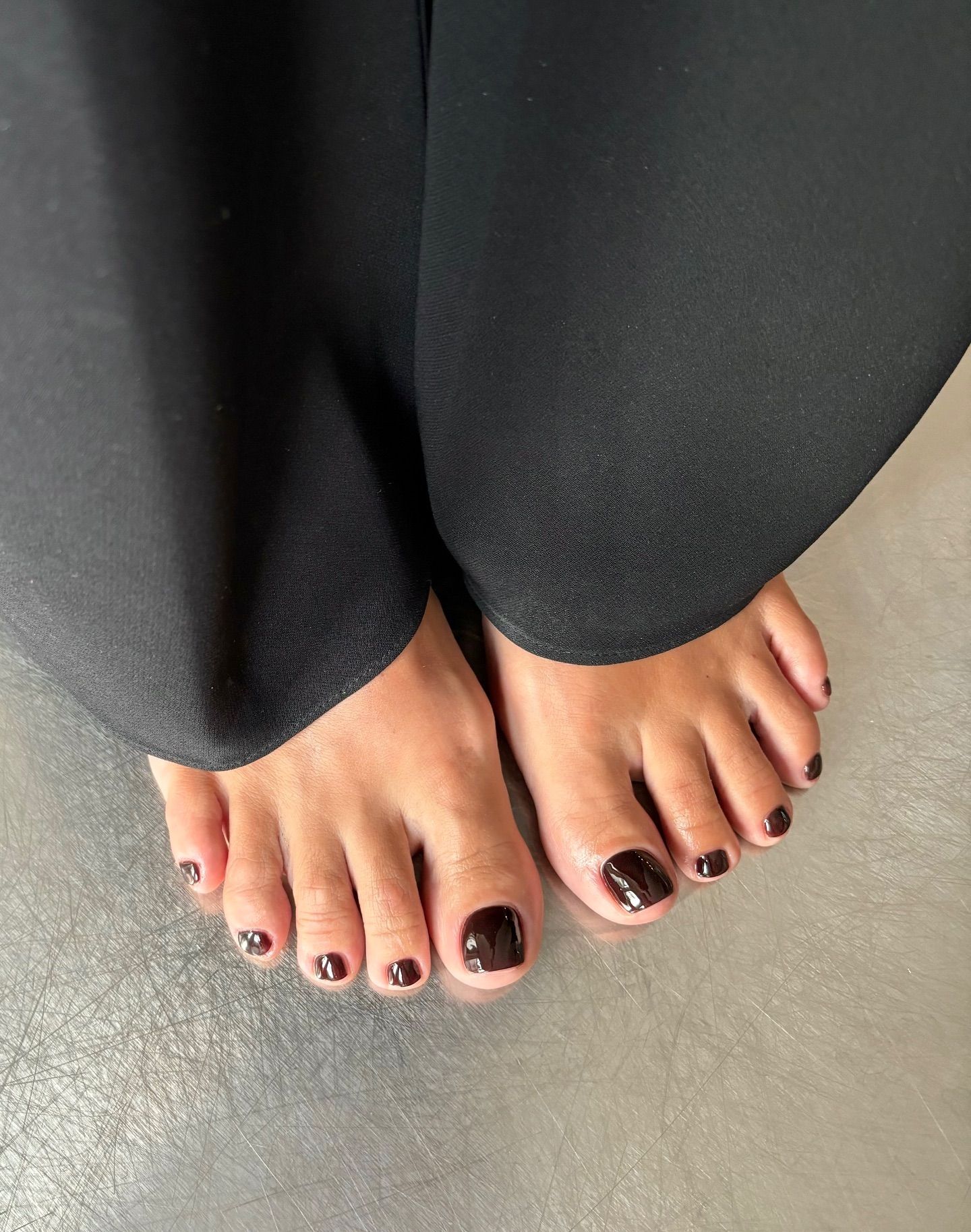 dark chocolate brown pedicure worn with long black trousers - autumnal pedicures 2026