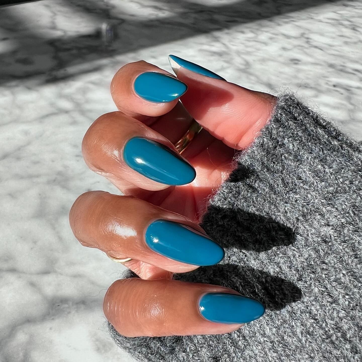 A close-up shot of a petrol blue manicure