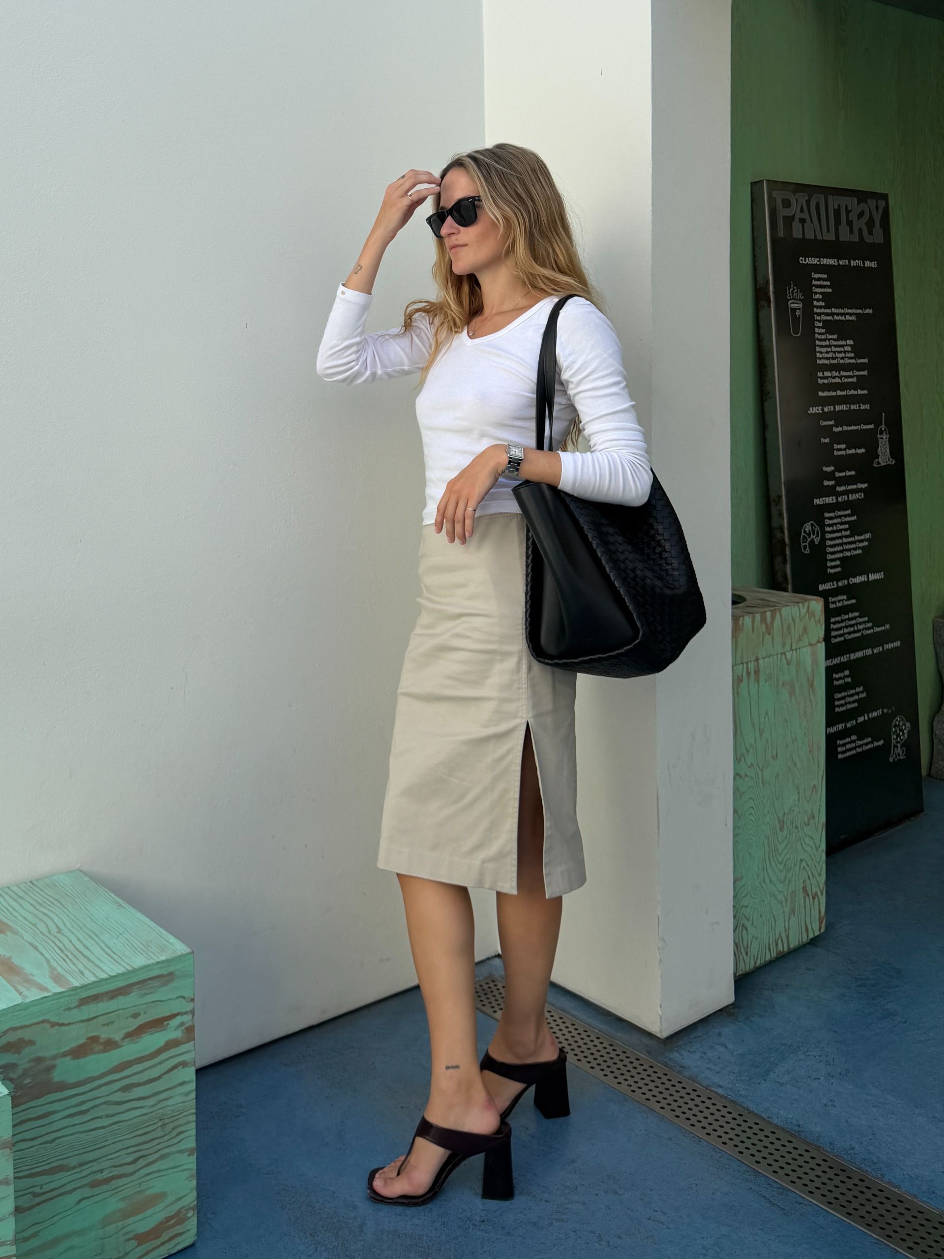 Eliza Huber wearing a white shirt, khaki skirt, and the new black Bottega Veneta Corso bag.