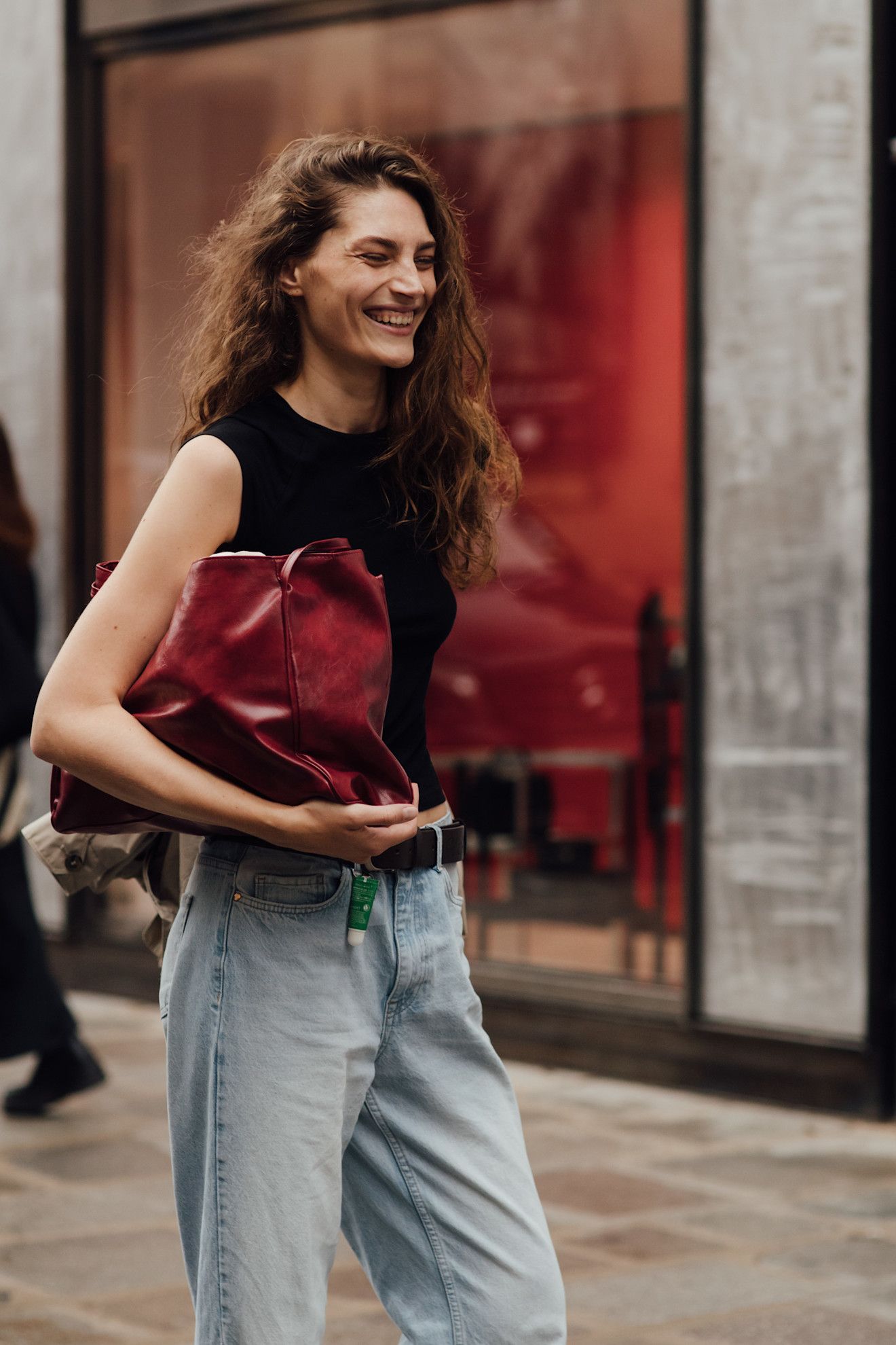 Paris Fashion Week attendee wears blue jeans with a red clutch bag.