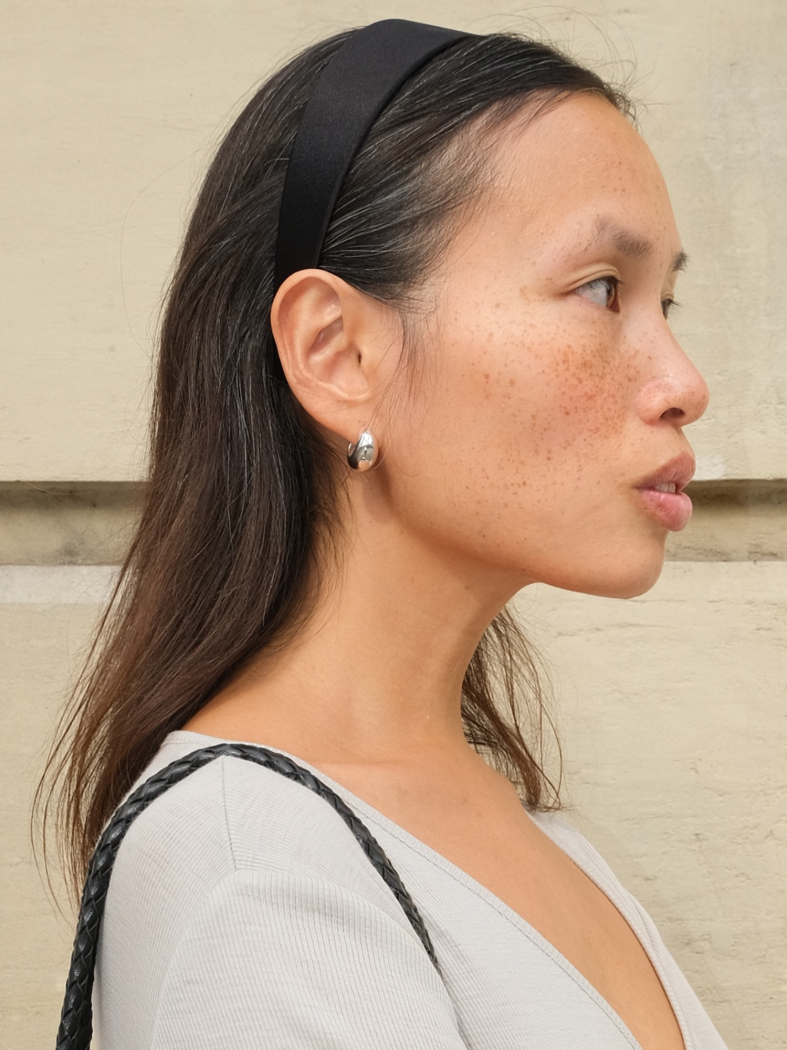 A woman with long hair, wearing a headband and a grey top
