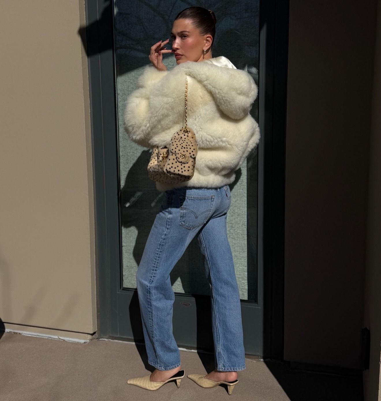 Hailey Bieber wearing a cream, fur jacket with vintage Levi's jeans and tan heels.