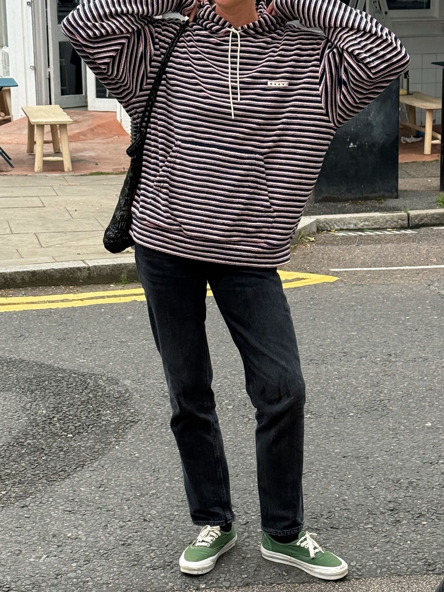 Influencer @lindseyholland_ poses for a photo wearing green Vans trainers with a striped hoodie and black jeans.