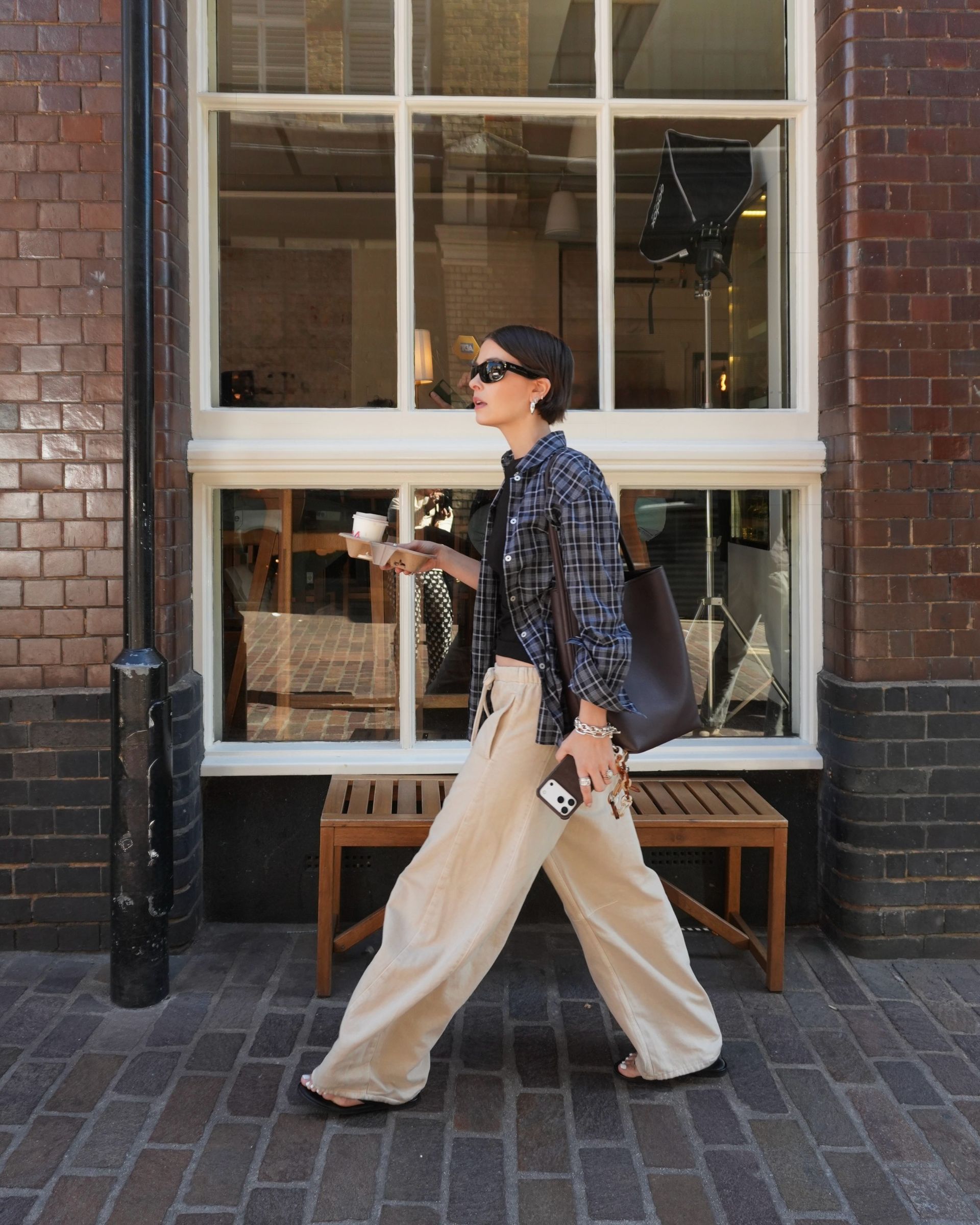 @thealiceedit shows how to wear a plaid shirt. She wears her shirt with tan trousers, flip-flops, and a fitted black tank top.
