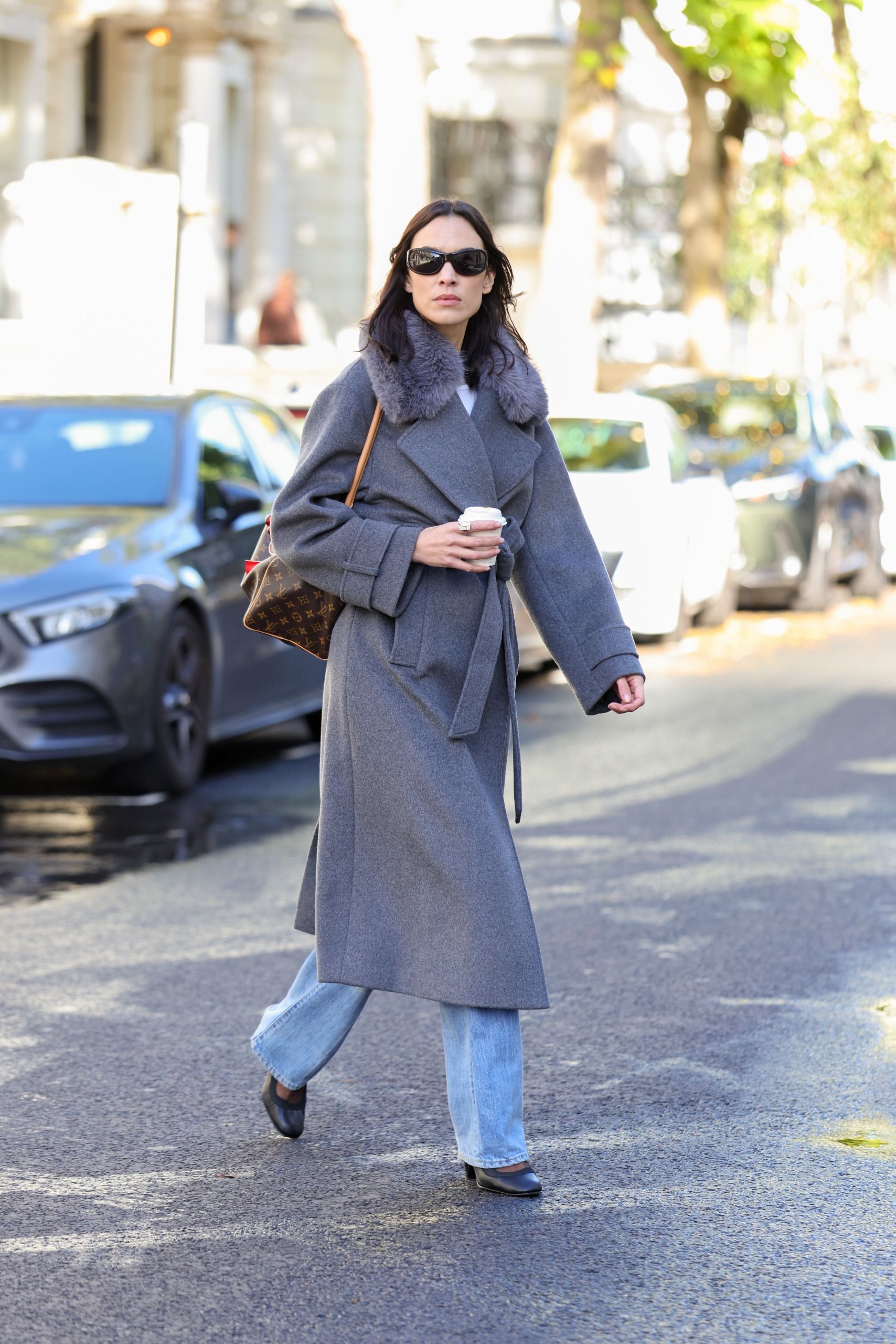 Alexa Chung walks down the street in London wearing an Aligne fur-trimmed grey coat with blue straight-leg jeans and pointed-toe heels.