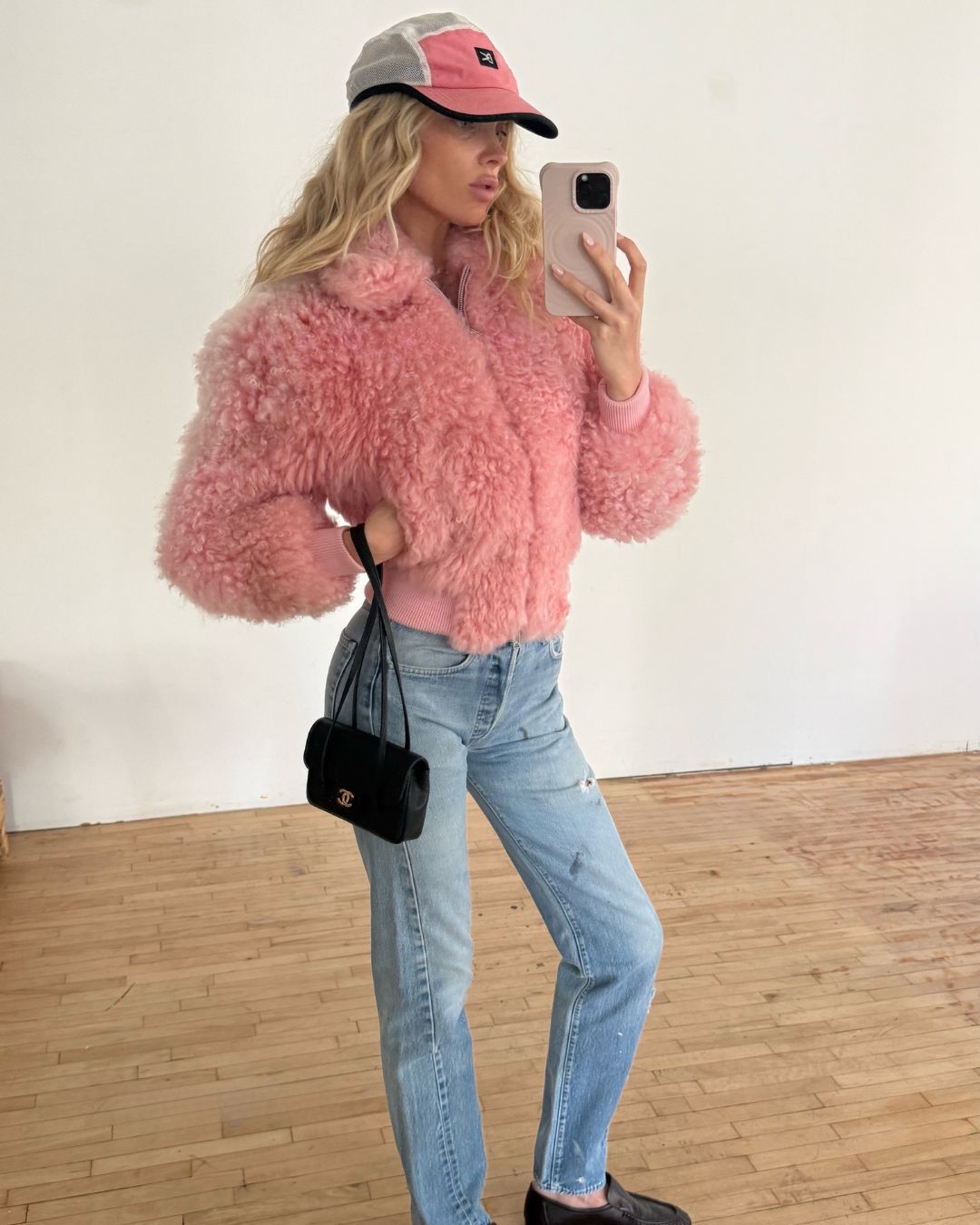 Elsa Hosk takes a mirror selfie wearing blue jeans with a pink fluffy jeans and black leather loafers