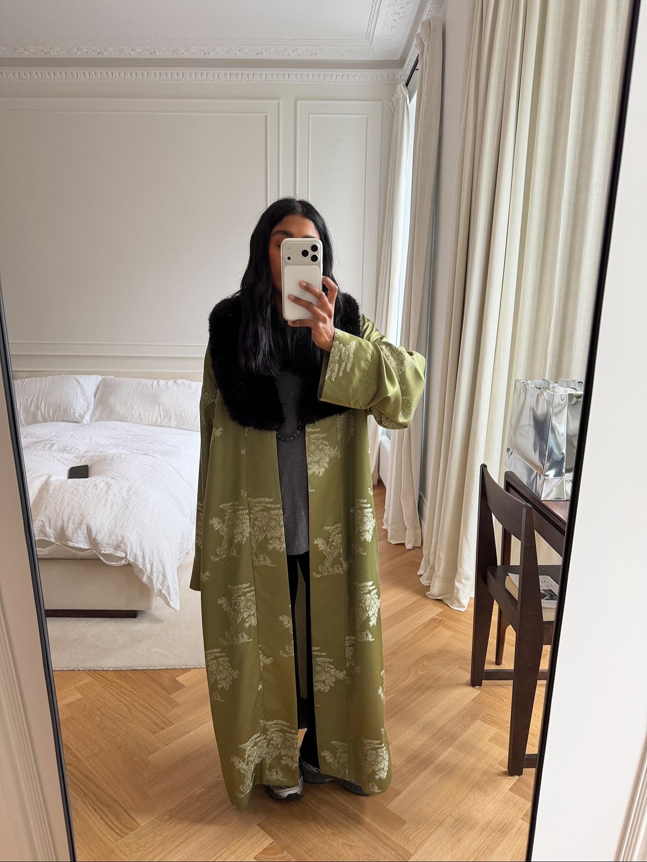 @monikh wears an olive green opera maxi coat with a brown faux fur collar