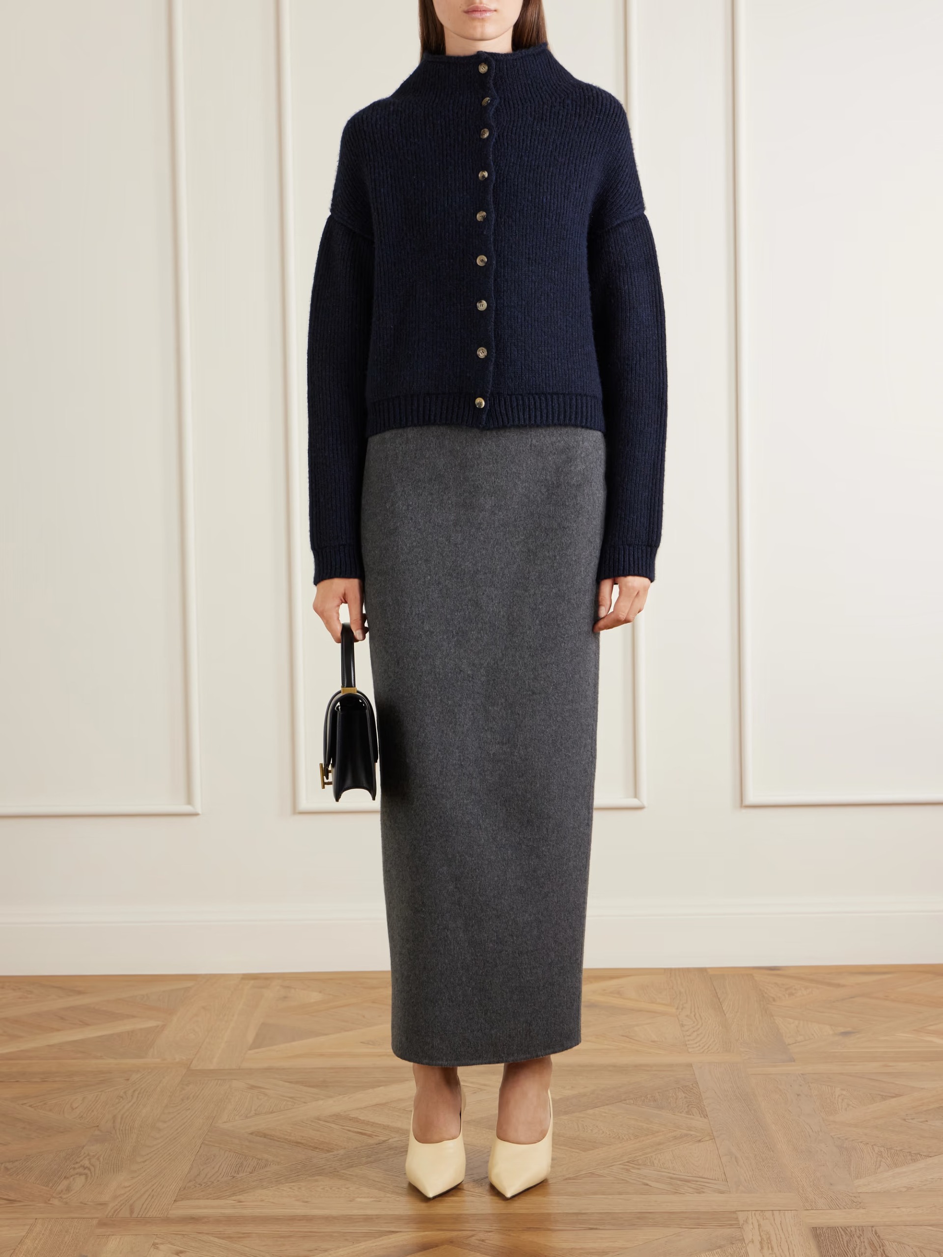 An image of a model wearing a long grey wool pencil skirt with a navy cardigan and cream heels