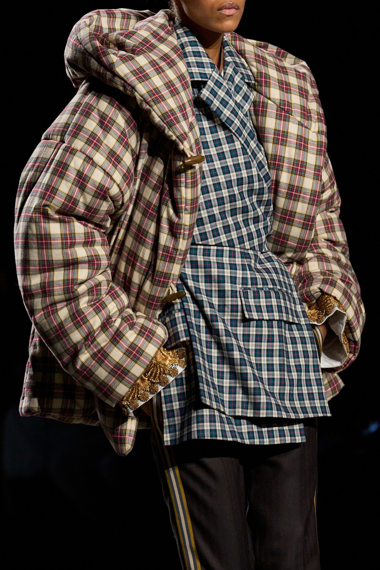 A model walks Dries Van Noten's A/W 27 runway in a checked puffer jacket layered over a checked blazer