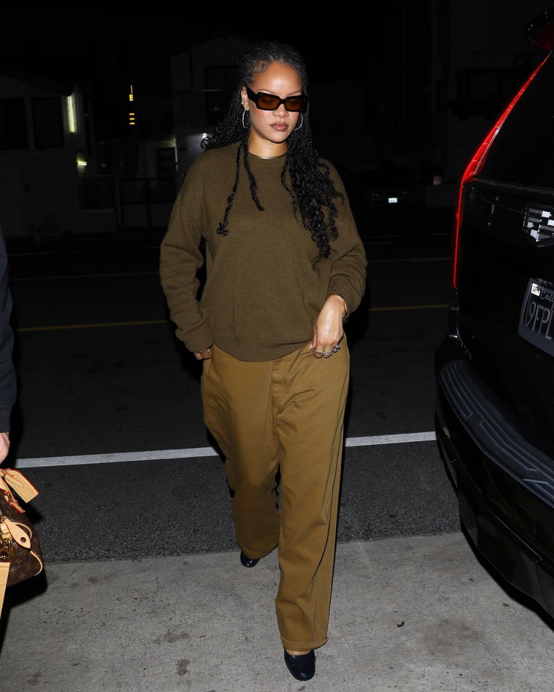 Rihanna steps out at night wearing a khaki jumper with khaki jeans and black ballet flats.