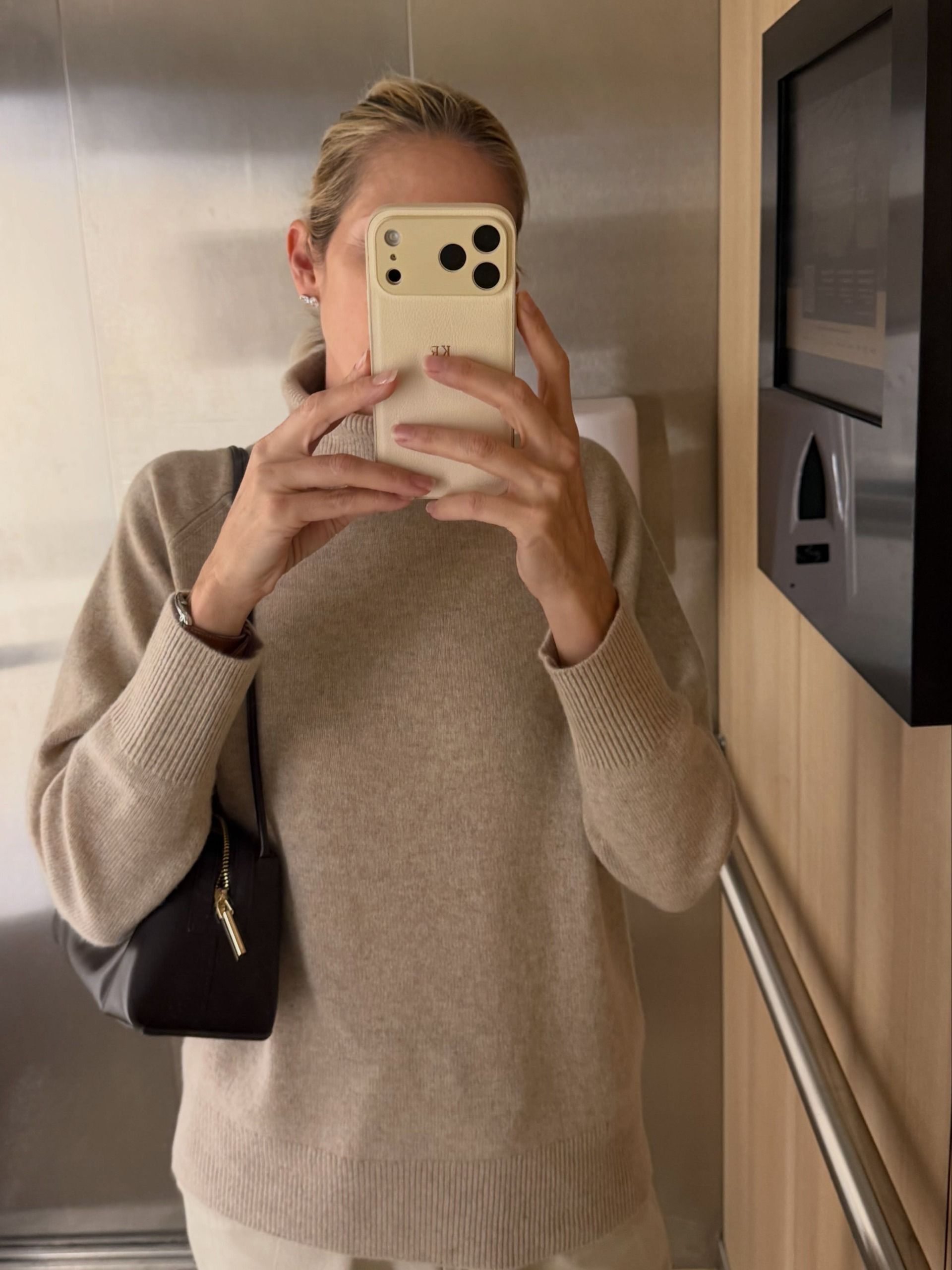 Kelly Rutherford takes a mirror selfie wearing an oatmeal knit with a black shoulder bag.