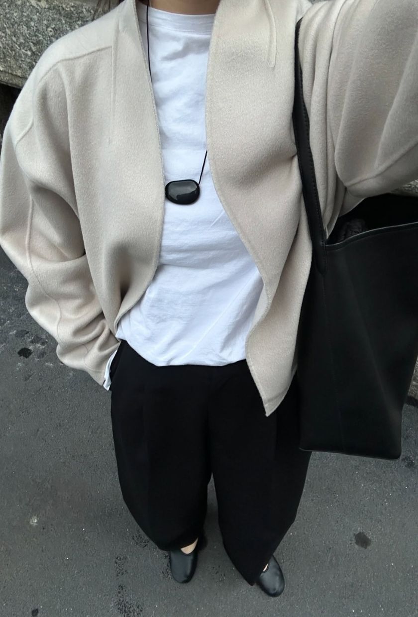 @selenamual wearing a cream wool jacket, white t-shirt, black tailored trousers, leather ballet flats, leather tote bag and black pendant cord necklace
