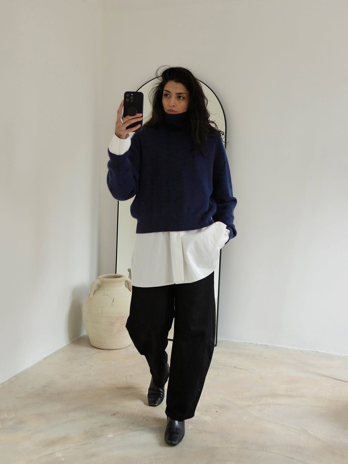 Woman wearing navy jumper, black trousers and a white shirt