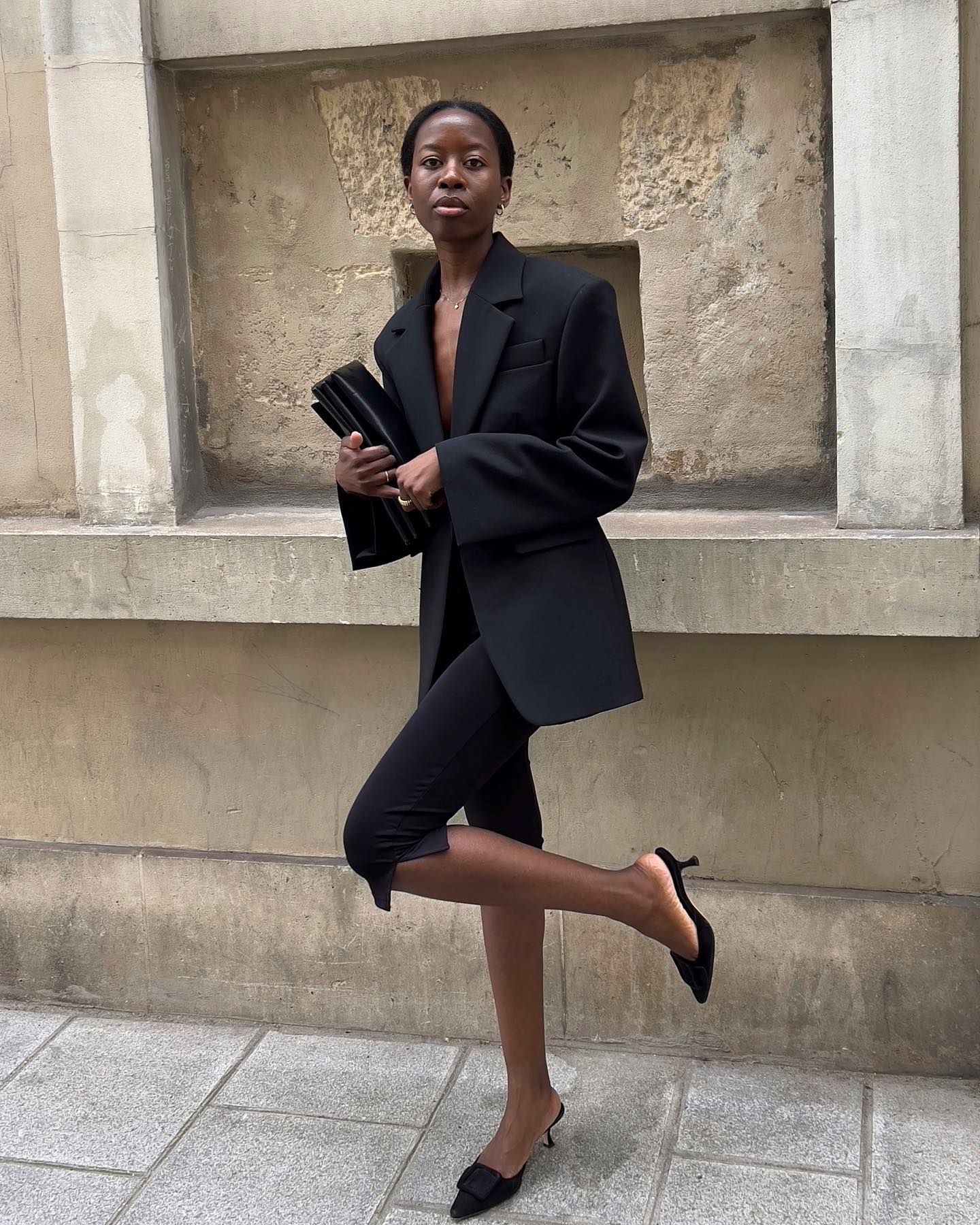 An image of @sylviemus_  wearing a black blazer with capri leggings and heeled mules.