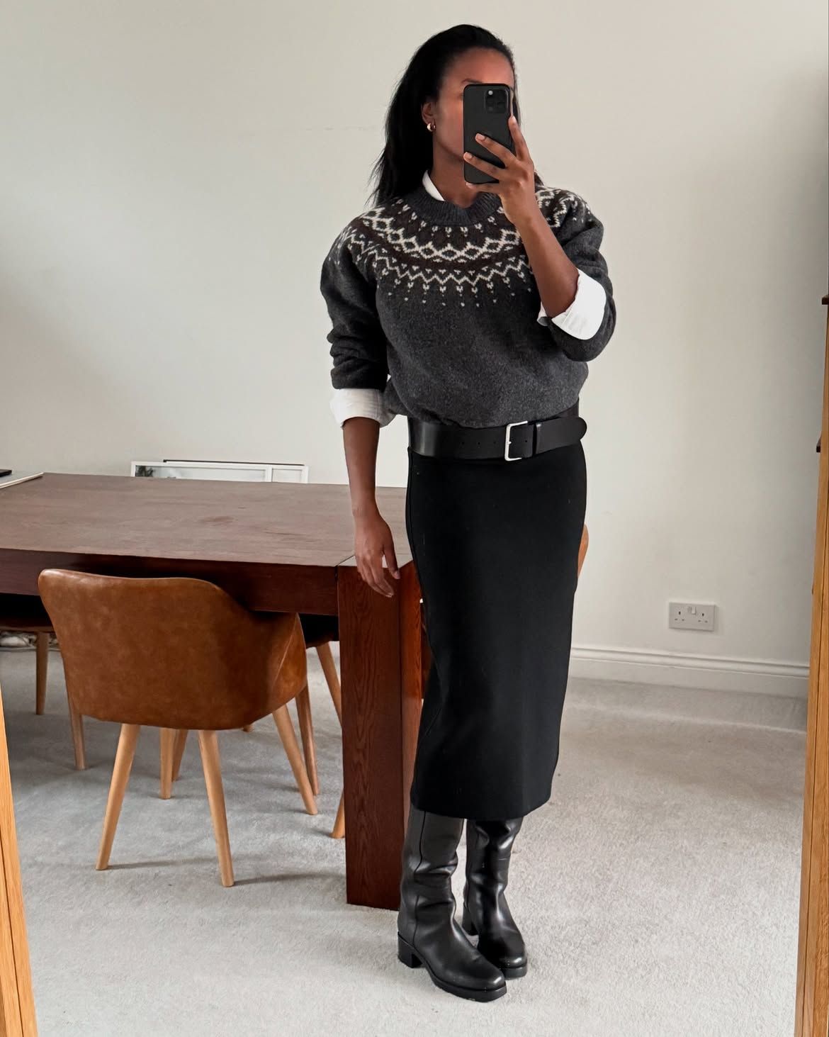 Woman wearing a fair isle jumper in grey, a pencil skirt and knee boots