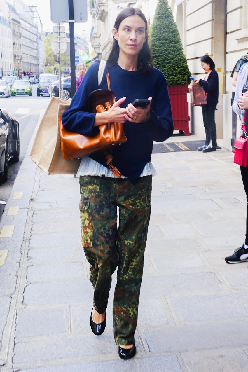 Alexa Chung wearing a navy sweater over a camisole with camo pants and black ballet flats