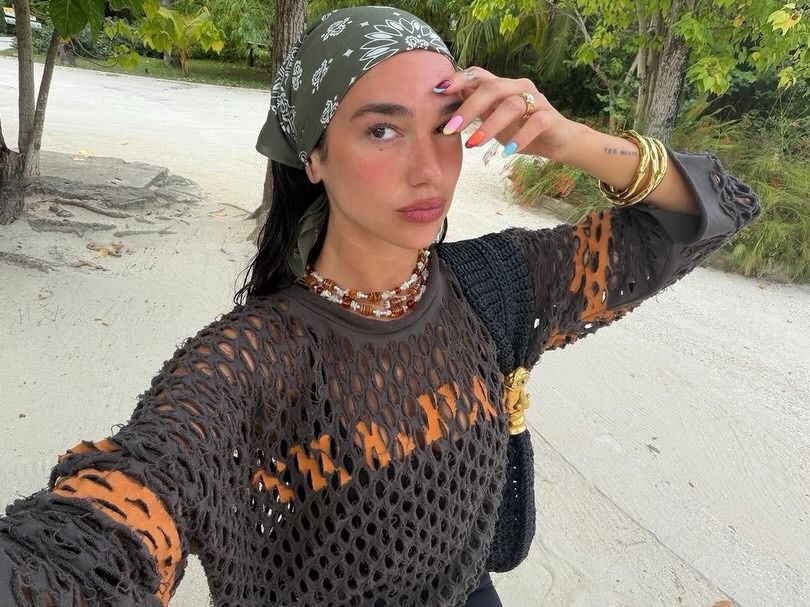 Dua Lipa with a contrasting colourful manicure on the beach