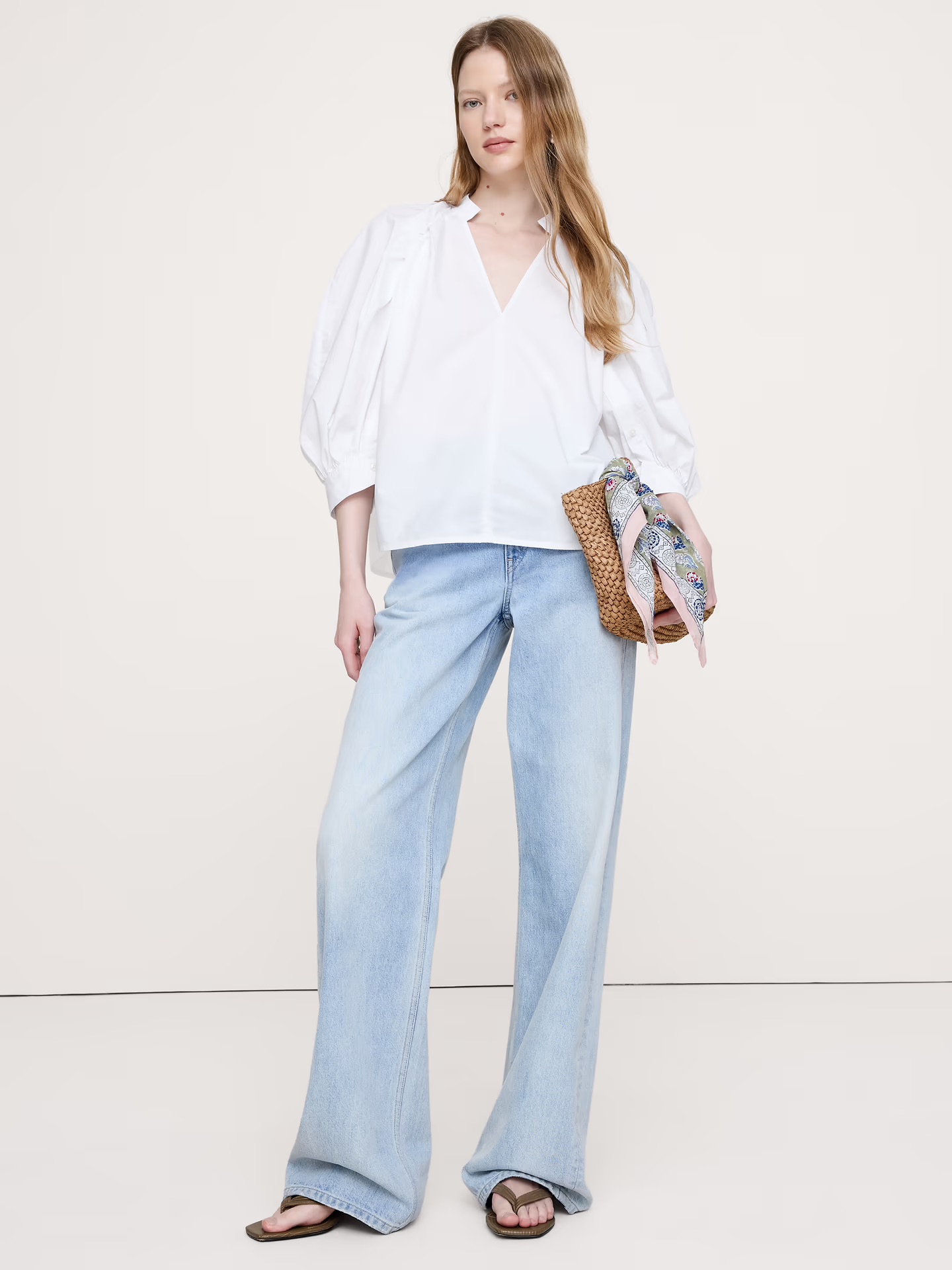 A model wears light blue jeans and a cotton poplin split-neck top in white by Banana Republic.