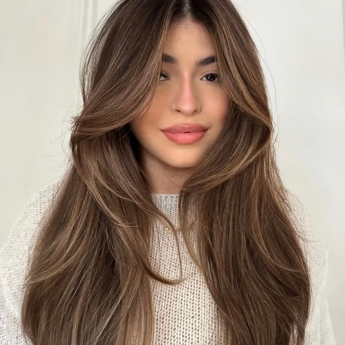 A woman with brown hair and neutral + warm highlights