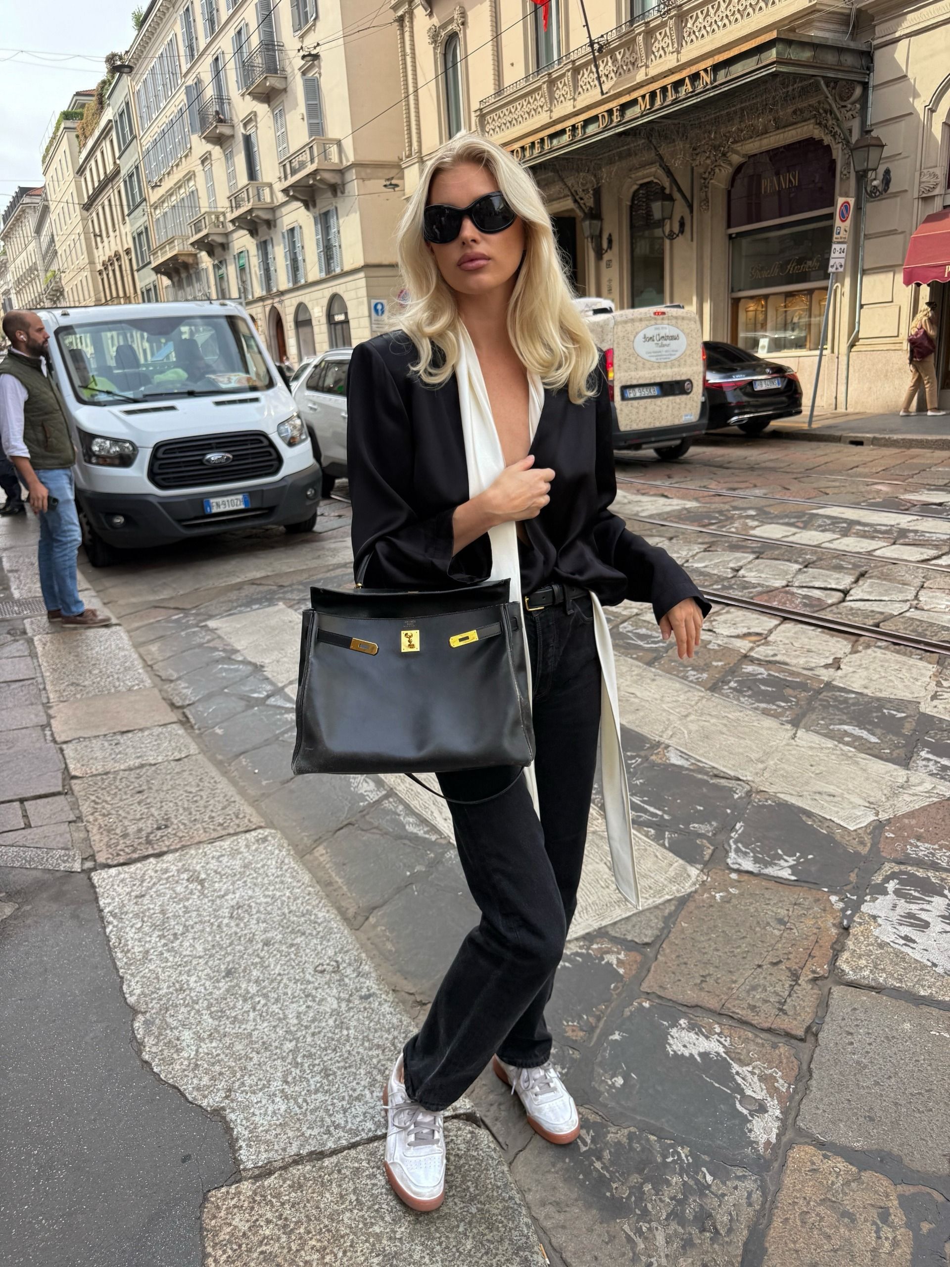 elsa wears a black satin top, white scarf, black jeans, white sneakers, and a black hermes bag.