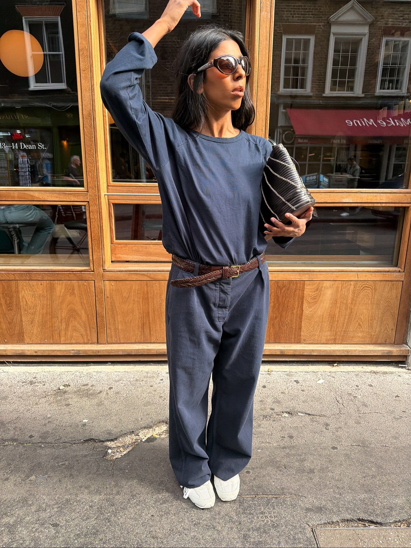 Monikh Dale wears a navy top, navy trousers from The Row, white trainers and a clutch bag